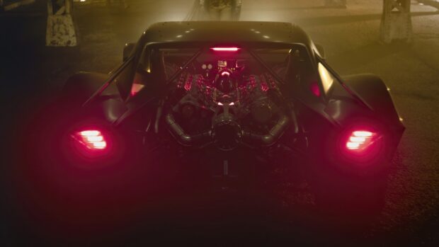 Rear view of the Batmobile showing its engine and glowing red lights at night