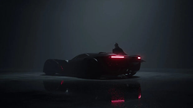 A sleek Batmobile parked in a dark setting with bright red rear lights illuminating the scene