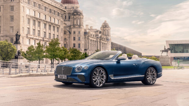 A blue Bentley Continental convertible parked near historic architecture in the city