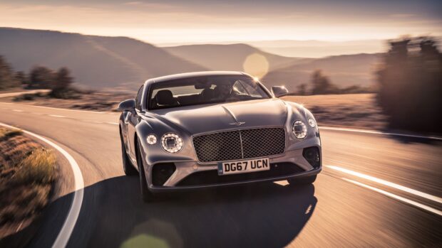 Bentley Continental driving on a winding road with mountains in the background