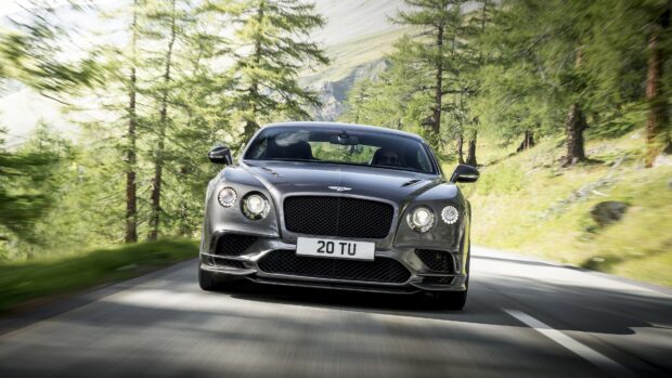 Front view of a Bentley Continental car driving on a forest road