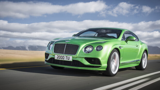 Green Bentley Continental driving fast on the road under cloudy sky