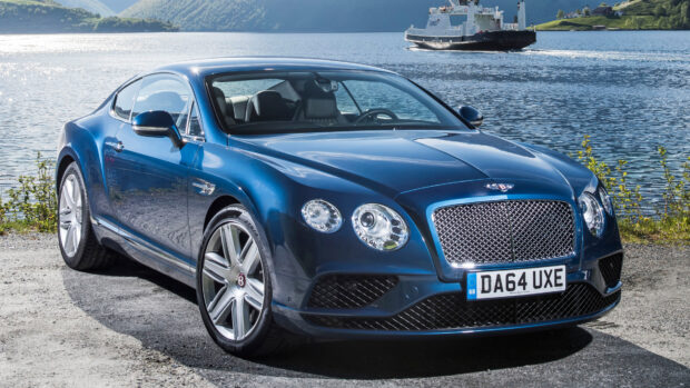A blue Bentley Continental car parked near a lake under clear sky