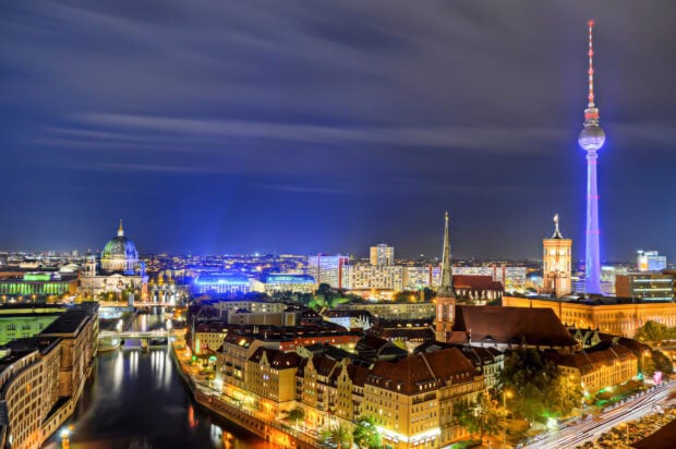 A vibrant Berlin skyline featuring historic buildings and illuminated TV tower at night
