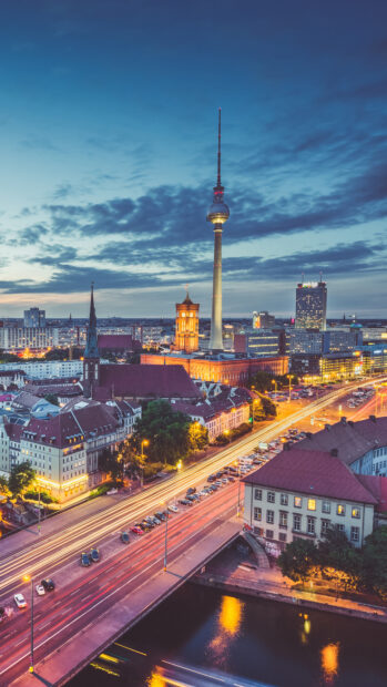 The Berlin skyline features the iconic TV tower and historic buildings under a twilight sky
