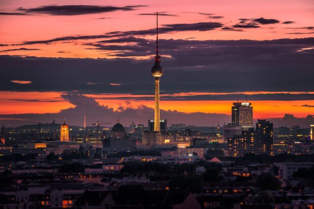 Berlin skyline at sunset with vibrant orange sky and city lights illuminating the buildings and TV tower