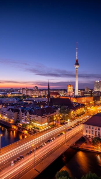 The Berlin city skyline with the iconic TV tower during sunset light trails on the streets