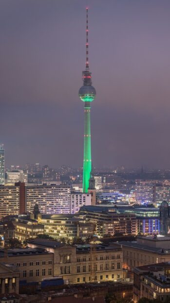 Berlin skyline featuring the iconic tv tower illuminated in green at dusk