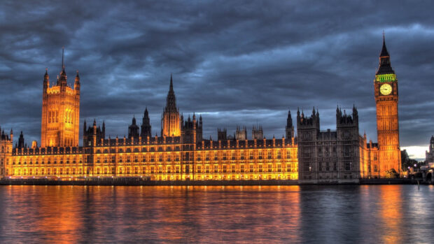 The illuminated Big Ben and Palace of Westminster under a cloudy evening sky