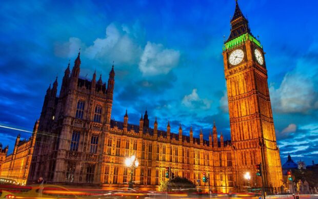 Big Ben tower illuminated at night with the historic building against a cloudy sky