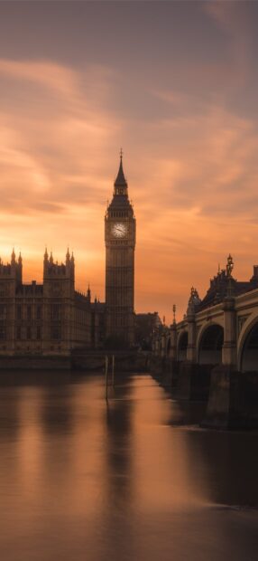 Big Ben tower stands tall over the river at sunset with a glowing sky