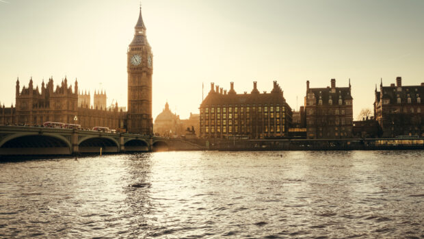 Big Ben tower with historic buildings along the river at sunset in London