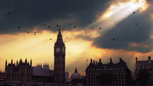 The iconic Big Ben tower stands tall against a dramatic sky with birds flying around