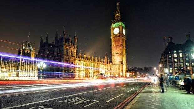 The illuminated Big Ben tower and palace of Westminster at night with light trails on the street