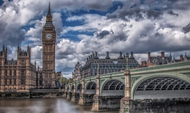The iconic Big Ben tower standing tall by the river under cloudy blue sky