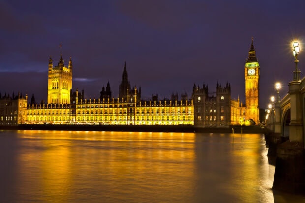 The illuminated Big Ben and surrounding buildings reflecting on the River Thames at night