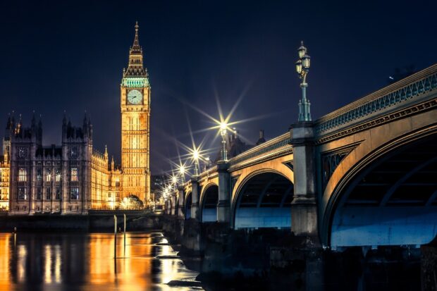 Illuminated Big Ben at night with bridge and river reflections in London