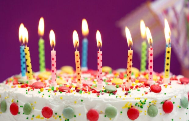 Colorful birthday cake with polka dot candles lit at a birthday party celebration