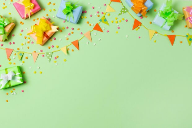Colorful birthday party decoration with gift boxes and festive flags on green background