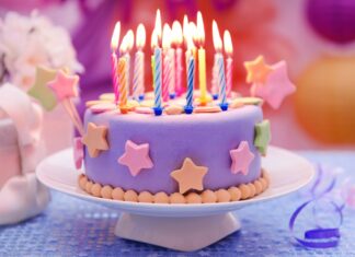 A birthday party cake decorated with colorful candles and star decorations for birthday celebration