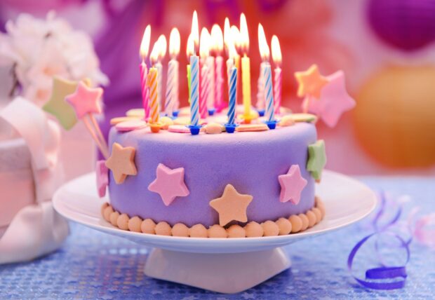 A birthday party cake decorated with colorful candles and star decorations for birthday celebration