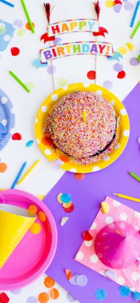 Colorful birthday celebration with cake and party decorations on a purple surface