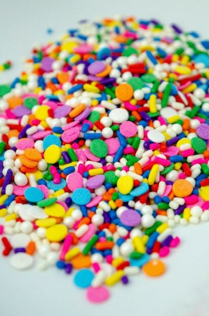 Colorful birthday party sprinkles scattered on a white surface for celebration