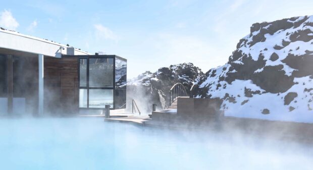 Hot spring steam rising in Blue Lagoon Iceland with snowy rocky mountains