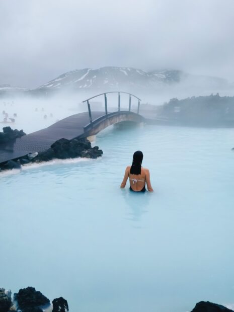 A woman enjoying the Blue Lagoon Iceland in calm geothermal waters under misty mountains