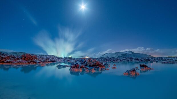 A serene view of Blue Lagoon Iceland with volcanic rocks and steam under a starry night sky