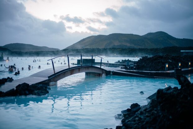 A scenic view of Blue Lagoon Iceland with geothermal water and people relaxing near volcanic rocks