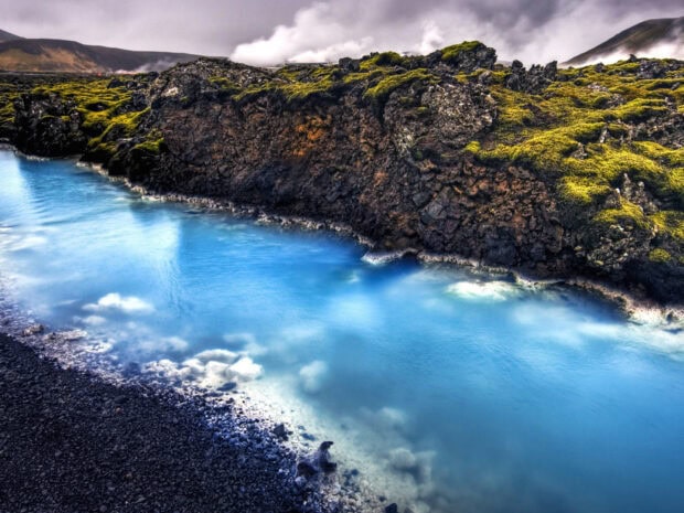 Blue Lagoon Iceland with rocky shore and vibrant moss landscape