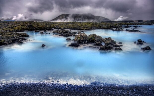 Blue Lagoon Iceland with rocky terrain and misty mountains in the background