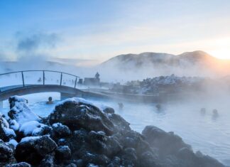 Blue Lagoon Iceland with steaming water and snow covered rocks at sunset