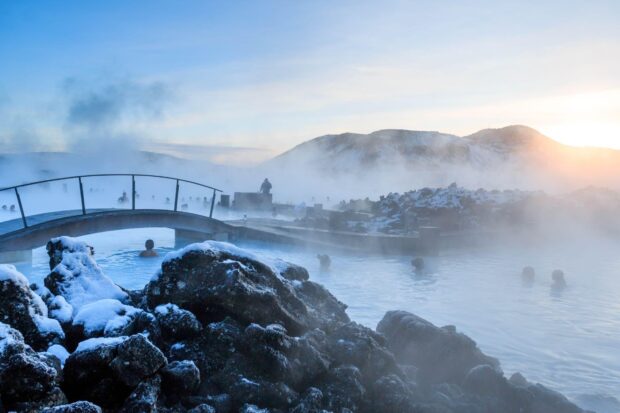 Blue Lagoon Iceland with steaming water and snow covered rocks at sunset