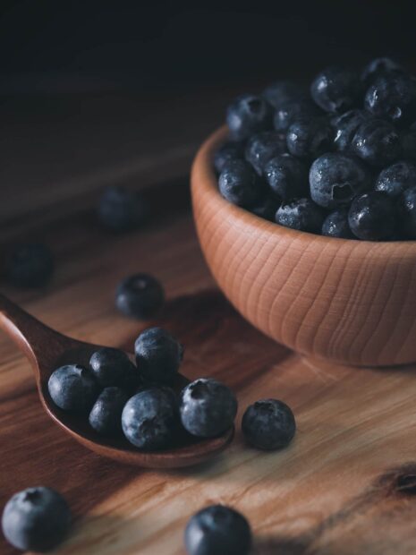 Fresh blueberry close up on a wooden spoon and bowl in natural light