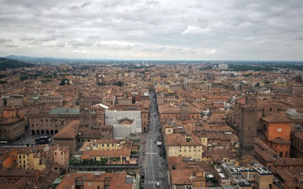 A panoramic view of Bologna city with historic buildings and streets under a cloudy sky