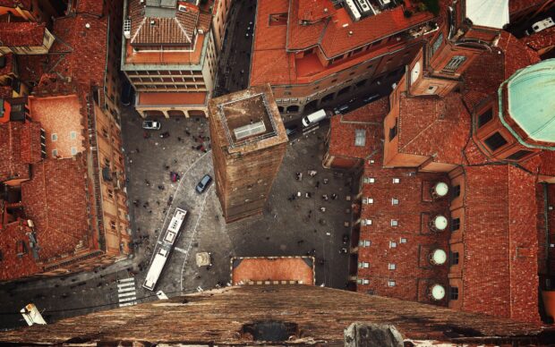 Aerial view of historic Bologna city with tall tower and red tiled roofs seen from above