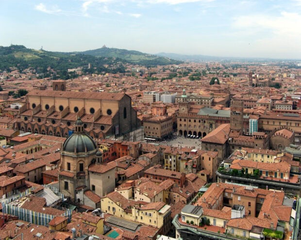 A panoramic view of Bologna city with historic buildings and red rooftops under a clear sky