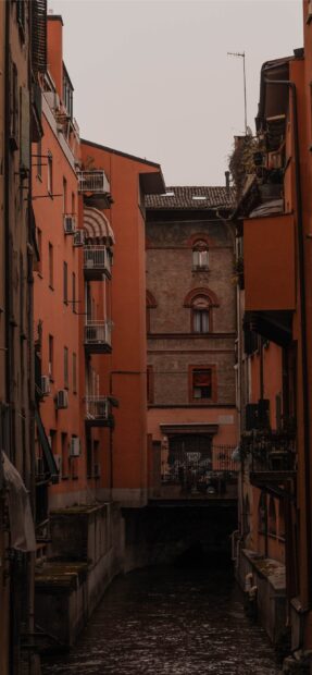 Narrow street canal view in Bologna with orange buildings and classic architecture
