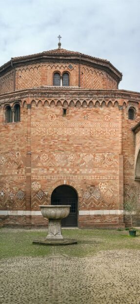 Historic architecture of Bologna with ornate brickwork and stone fountain in courtyard