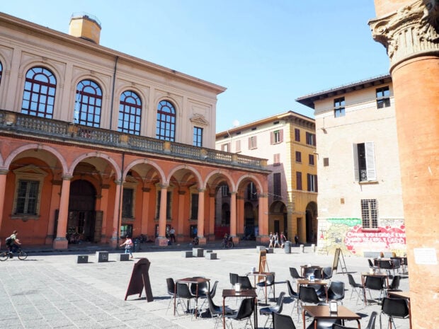 Historic architecture and outdoor seating in Bologna city square with clear blue sky