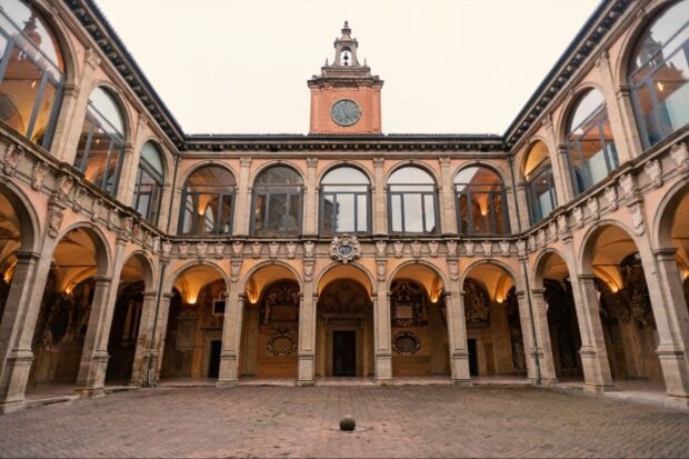 Historic architecture of Bologna with arches and a clock tower in the courtyard