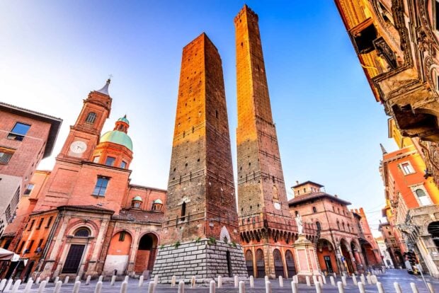 Historic towers and architecture in Bologna cityscape at sunrise with clear blue sky