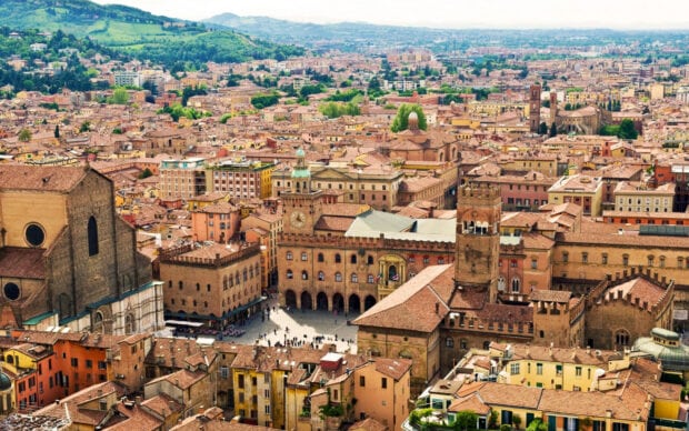 The historic center of Bologna with old buildings and a medieval clock tower in a cityscape view