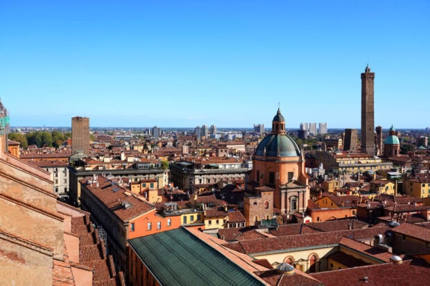 A panoramic view of Bologna cityscape featuring historic architecture and towers under clear blue sky
