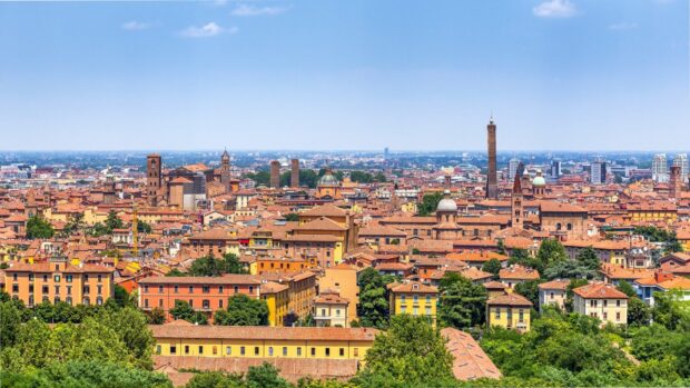 A panoramic view of Bologna cityscape with historic towers and colorful buildings under a clear sky