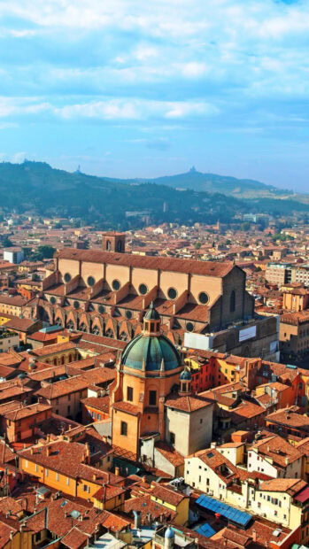 Historic architecture and cityscape of Bologna with a prominent dome structure under blue sky