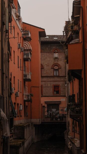 Narrow canal flowing between historic buildings in Bologna cityscape