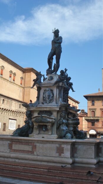 The Neptune statue stands tall in Bologna city center with historic buildings surrounding the fountain